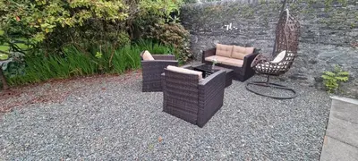 a group of wicker chairs and an umbrella on gravel at 2 bed Lodge near Dunoon on the Shore Front in Dunoon