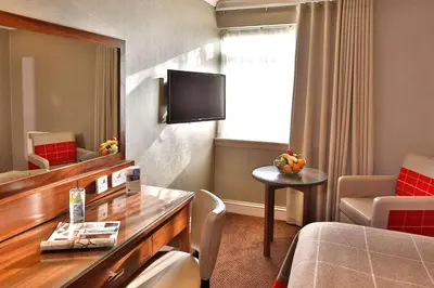 a hotel room with a bed and a table and a tv at Best Western Motherwell Centre Moorings Hotel in Motherwell
