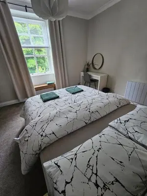 a bedroom with two beds and a window at Glebe Apartment in Campbeltown