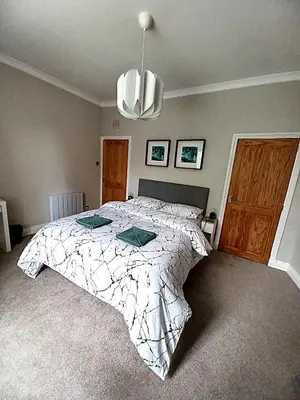 a bedroom with a large bed with a white comforter at Glebe Apartment in Campbeltown