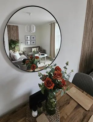 a mirror on a table with a vase of roses at Glebe Apartment in Campbeltown
