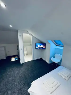 a room with a bed and a bathroom with a television at Modern 2 bedroom House With Loft Conversion in Glasgow