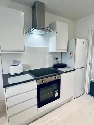 a kitchen with white cabinets and a stove top oven at Modern 2 bedroom House With Loft Conversion in Glasgow