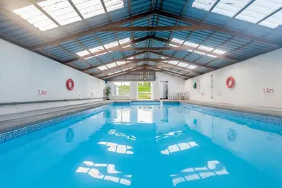 a large indoor swimming pool with blue water at Courtyard Cottages Granary Cottage in Wigtown