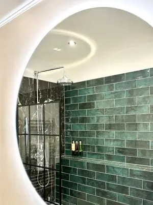 a bathroom mirror with a green tiled wall at St Johns Jailhouse by the Castle in Stirling