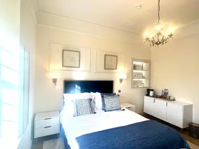 a bedroom with a large bed and a chandelier at 'Hamish' in ApartNest Auchterarder in Auchterarder