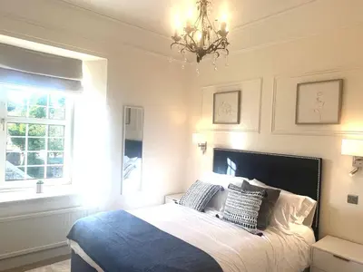 a bedroom with a large bed and a chandelier at 'Hamish' in ApartNest Auchterarder in Auchterarder