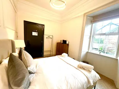 a bedroom with a white bed with pillows and a window at 'Mac' in ApartNest Auchterarder in Auchterarder