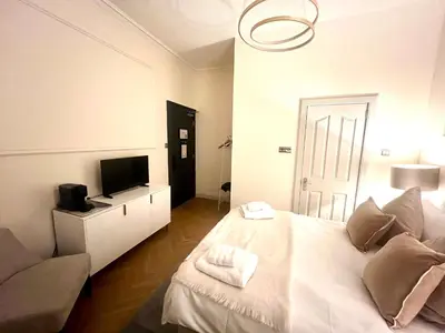 a white bedroom with a bed and a television at 'Maisie' in ApartNest Auchterarder in Auchterarder