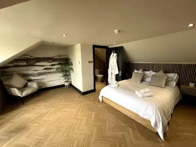 a bedroom with a large white bed and a chair at 'Clyde' in ApartNest Auchterarder in Auchterarder