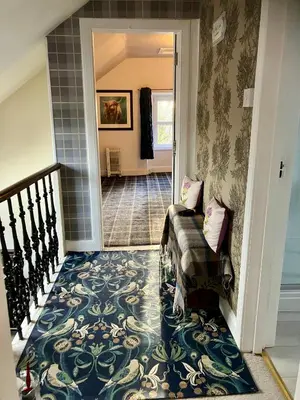 a hallway with a staircase with a blue and white carpet at Above & Beyond at Warriston Lodge in Moffat