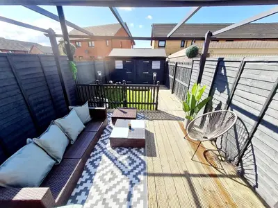 a patio with a couch on a balcony at Lovely house with back garden - PRIVATE driveway in Glasgow