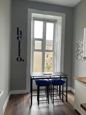a dining room table with blue chairs in front of a window at West End Cosy Pop of Colour - Pass the Keys in Glasgow