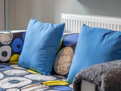 a couch with two blue pillows on it at West End Cosy Pop of Colour - Pass the Keys in Glasgow