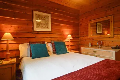 a bedroom with a bed in a log cabin at Rowan Log Cabin in Dalavich
