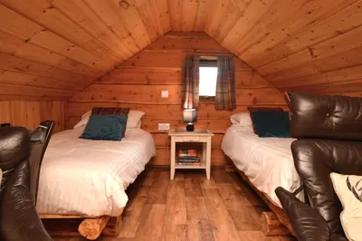 two beds in a log cabin with a window at Rowan Log Cabin in Dalavich