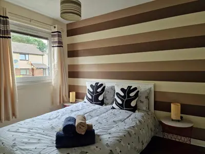 a bedroom with a bed with brown and white stripes at Yuriko in Saint Davids