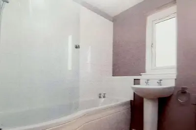 a white bathroom with a sink and a bath tub at Yuriko in Saint Davids