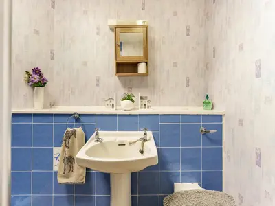 a bathroom with a white sink and blue tiles at Carraig Dhubh Cottage - Uk47123 in Whiting Bay