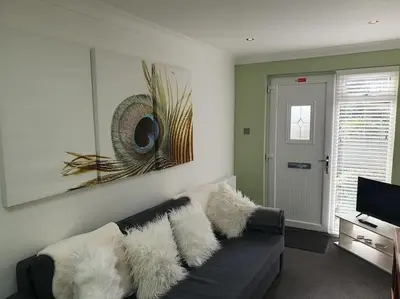 a living room with a black couch with white pillows at THE ELFIN- Lovely 1 Bedroom - Free Parking in Bridge of Allan