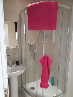 a bathroom with a shower with a sink and pink towels at THE ELFIN- Lovely 1 Bedroom - Free Parking in Bridge of Allan