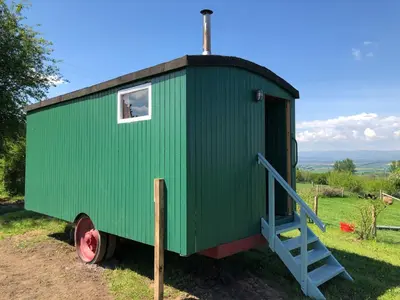 a green tiny house with a ladder in a field at The Bothy and Wagon at Pitmeadow Farm in Perth