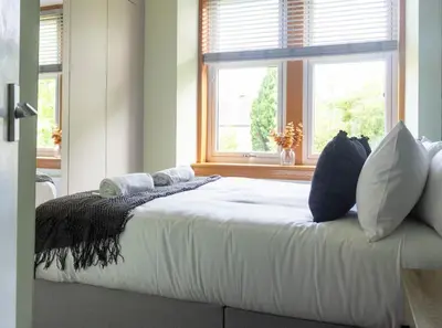 a bedroom with a bed with pillows and a window at 1 BDR Apt At Caledonia Luxe Stays Short Lets & Serviced Accommodation Paisley in Paisley