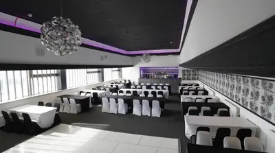 a banquet hall with white chairs and a chandelier at Hardgate House Hotel in Clydebank