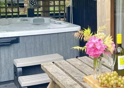 a table with a vase of pink flowers and a tub at Seil Log Cabin in Dalavich