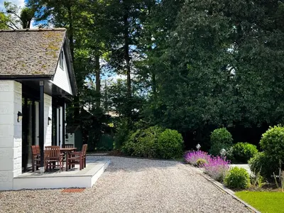 a cottage with a table and chairs on a gravel driveway at Large and luxurious country home near Glasgow in Eaglesham