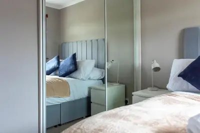 a mirror in a bedroom with a bed with blue pillows at Croftspar House in Glasgow