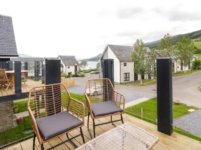two chairs on a deck with a view of a street at Kalipé in Aberfeldy