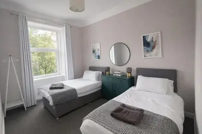 a bedroom with two beds and a mirror and a window at Beautiful spacious apartment in town centre in Oban