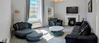 a living room with two couches and a table at Beautiful spacious apartment in town centre in Oban