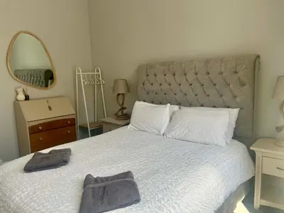 a bedroom with a large bed with a mirror at Beautiful spacious apartment in town centre in Oban
