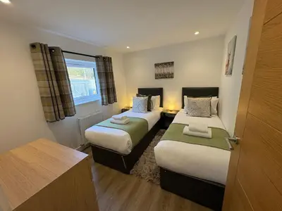 a small bedroom with two beds and a window at The Gîte in the Highlands in Acharra
