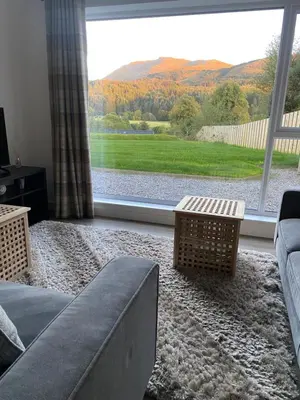 a living room with a couch and a large window at The Gîte in the Highlands in Acharra