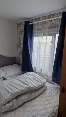 a bed with a blue curtain and a window at Static Caravan situated at Wigbay, Stranraer in Stranraer