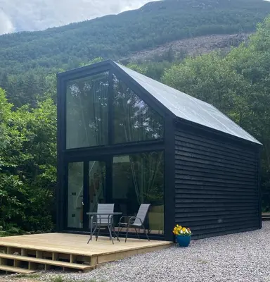 a black cabin with a table and chairs in it at Aos Sí - Wellness - Jacuzzi - Lodges in Ballachulish