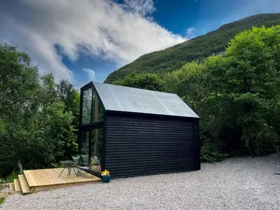 a small black cabin with a solar roof at Aos Sí - Wellness - Jacuzzi - Lodges in Ballachulish