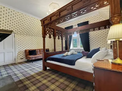 a bedroom with a canopy bed and a couch at St John's Old Rectory in Glencoe