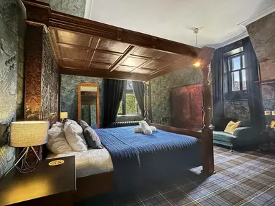 a bedroom with a large canopy bed with blue sheets at St John's Old Rectory in Glencoe
