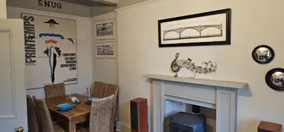 a living room with a table and a fireplace at Snug - Macushla Apartment in Helensburgh