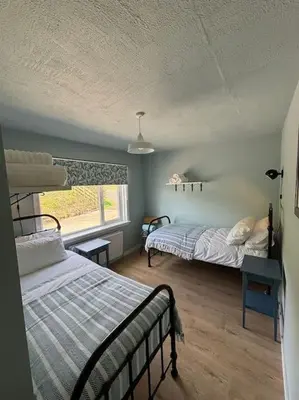 a bedroom with two beds and a window at Stunning Rathlin cottage in Rathlin Island