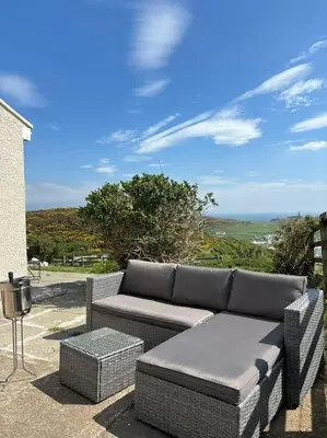 a wicker couch and stool on a patio at Stunning Rathlin cottage in Rathlin Island