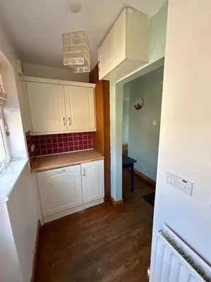a kitchen with white cabinets and red tile on the wall at Beachside House Rathlin Island in Rathlin Island