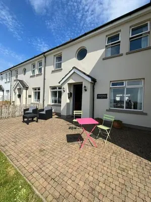 a pink table and chairs in front of a house at Beachside House Rathlin Island in Rathlin Island