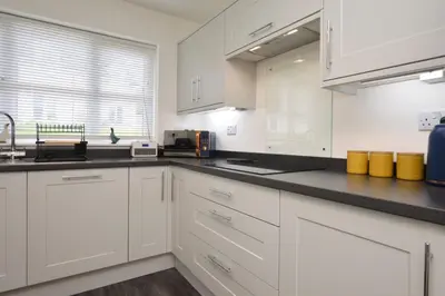 a kitchen with white cabinets and a black counter top at Kilin in Lochgilphead