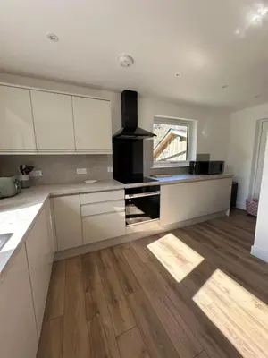 a kitchen with white cabinets and a wooden floor at Highland Hideaway in Fort William