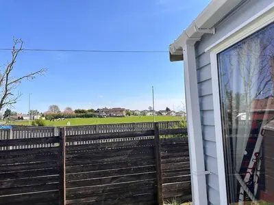 a wooden fence next to a house with a field at Swift 3-Bedroom Caravan Located in Uddingston, Glasgow at Maryville Caravan Site in Uddingston
